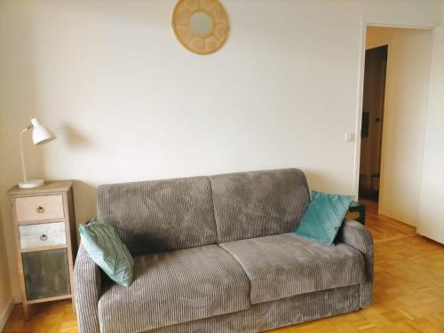 - un canapé dans le salon doté d'une horloge murale dans l'établissement T3 Centre ville & Lac, Balcon, Garage, à Annecy