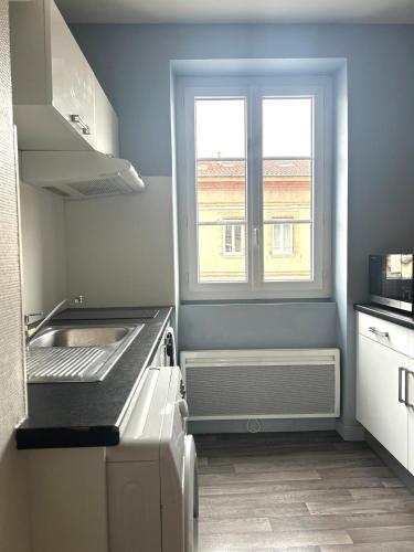 une petite cuisine avec un évier et une fenêtre dans l'établissement Le Holly - Appartement centre ville Climatisé, à Albi