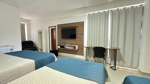 a hotel room with two beds and a desk at Hotel Skalla - MELHOR CUSTO BENEFICIO in Teixeira de Freitas