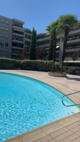 une piscine bleue avec des palmiers et un bâtiment dans l'établissement App B, à Lyon
