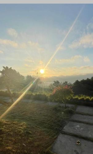 a sun is shining on a field with the grass at The Breezy Volcano in Kintamani