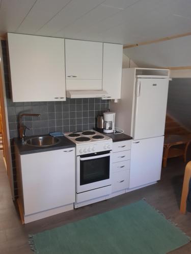 a kitchen with white cabinets and a stove and a sink at penthouse casinonsaari in Savonlinna