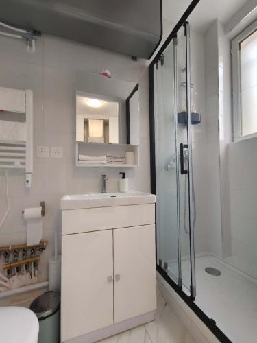 une salle de bain blanche avec un lavabo et une douche dans l'établissement Belleville 10, à Paris