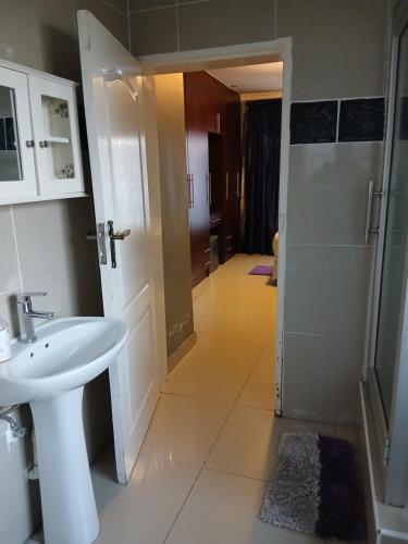 a bathroom with a white sink and a shower at Kimberland Guest House Block 10 in Gaborone