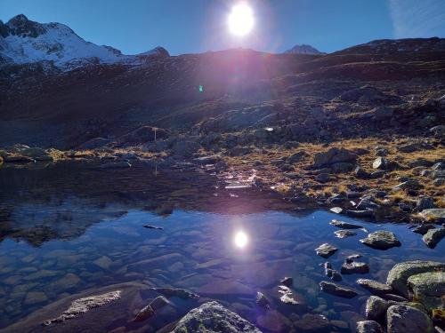a reflection of the sun in a mountain lake at Alpenchalet Lengau in Dornauberg