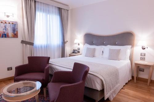 a hotel room with a bed and two chairs at Borgo La Chiaracia Resort & SPA in Castel Giorgio