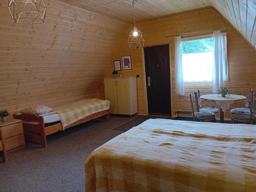 a bedroom with a bed and a table and a window at Zakątek Włóczykija in Cisna
