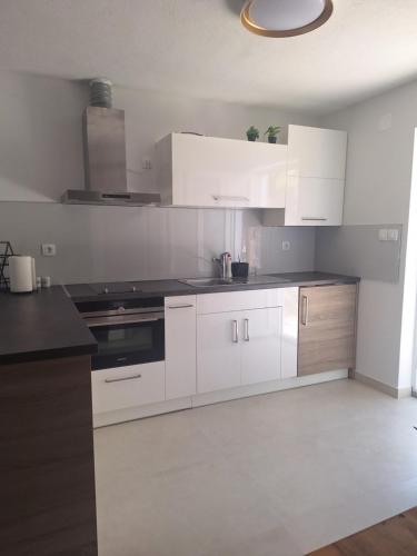 Una cocina con gabinetes blancos y encimeras negras. en Smokvica, en Senj