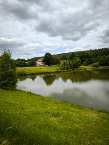 a large lake with a house in the distance at Farma Hájenka in Třemošná