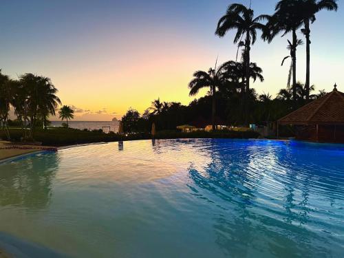 a large swimming pool with palm trees and a sunset at Studio Evasion Coco vue Jardin Tropical - Pierre & Vacances in Sainte-Luce