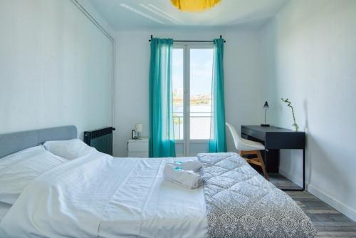 - une chambre avec un lit blanc, un bureau et une fenêtre dans l'établissement Grand T5 de 103 m2 au Bd Guigou avec 4 balcons, à Marseille