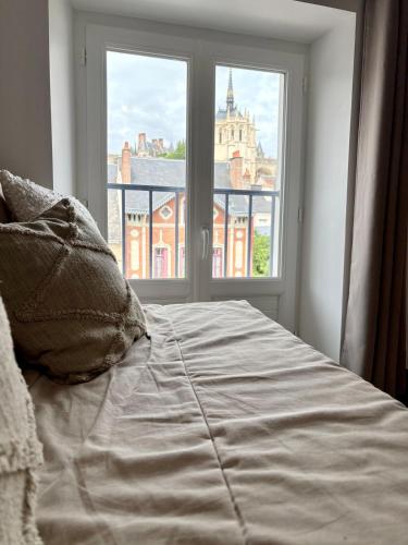 a bed in front of a window with a view at Sejour de charme au bohème in Amboise