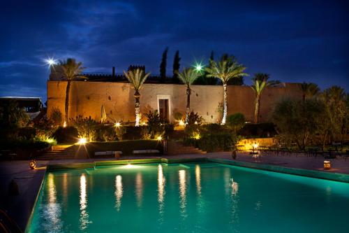 a swimming pool in front of a building at night at Kasbah Agafay Hotel & Spa in El Karia