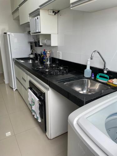a kitchen with a sink and a stove at Apto condomínio Ônix in Campos dos Goytacazes