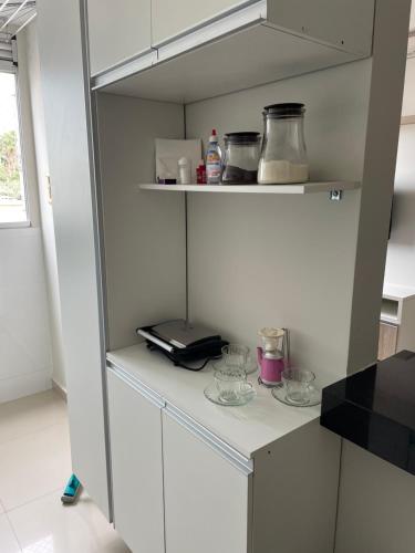a kitchen with a shelf with bowls on it at Apto condomínio Ônix in Campos dos Goytacazes