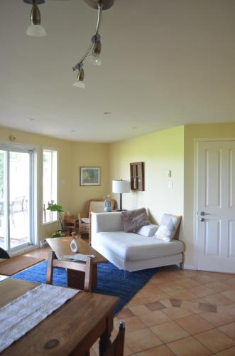 a living room with a white couch and a table at Suite-appartement 2 chambres à la campagne. Rez de jardin in Dunham