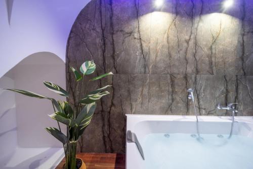 a bathroom with a tub and a plant in a vase at Le suite di Alba in Palermo