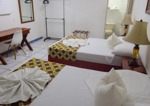 two beds in a room with a table and a desk at La Posadita de Bolonia in Managua