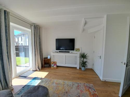 una sala de estar con TV de pantalla plana en un armario blanco en Elm Grove, en Hirwaun