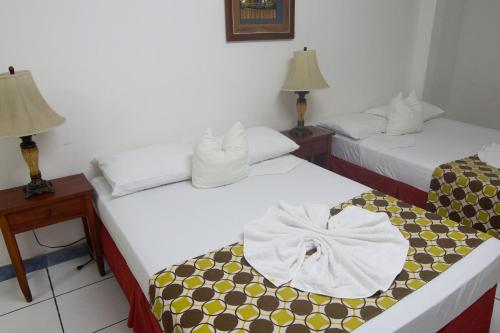 two beds in a room with two lamps at La Posadita de Bolonia in Managua