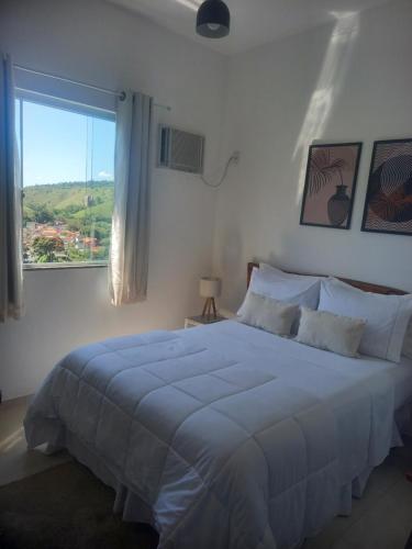 a white bedroom with a large bed and a window at Linda suíte confortável e com linda vista 101 in Conservatória