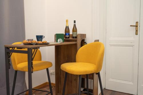 a kitchen with yellow chairs and a table with bottles of wine at Le suite di Alba in Palermo