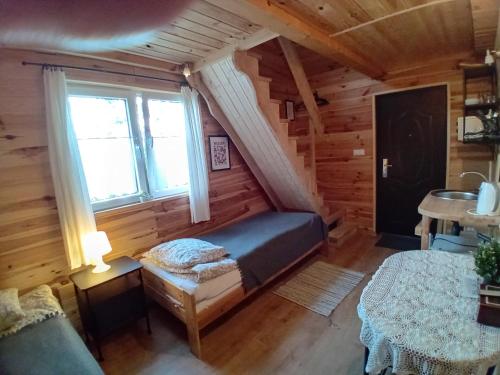 a bedroom in a log cabin with a bed and a window at Zakątek Włóczykija in Cisna