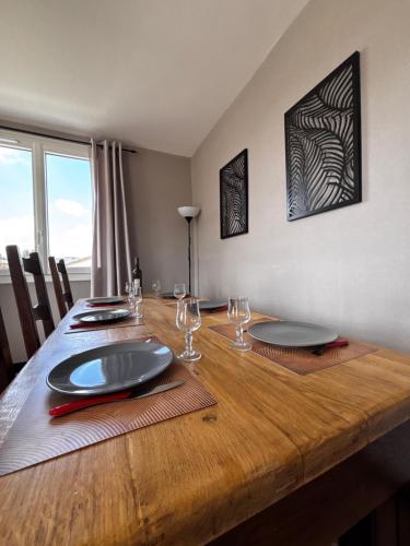une table en bois avec des assiettes et des verres à vin dessus dans l'établissement Gîte 6 personnes Aubenas, à Saint-Didier-sous-Aubenas