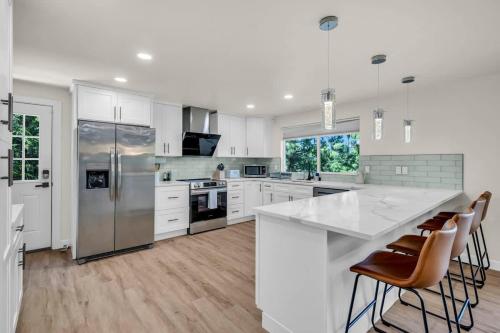 a kitchen with white cabinets and a large island with bar chairs at Exclusive Lakefront For 10 with Sauna Kayaks Peace in Snohomish