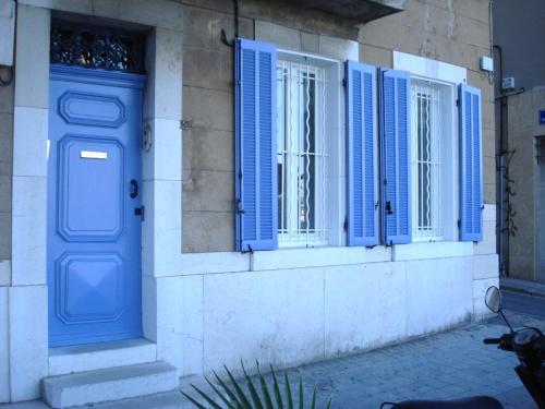 un bâtiment avec des fenêtres à volets bleus et une porte bleue dans l'établissement Joli appartement bord climatisé emplacement idéal, à La Ciotat