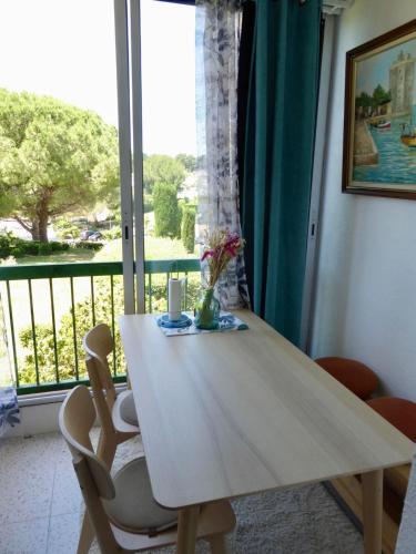 une table en bois avec deux chaises et une fenêtre dans l'établissement Studio - La baie des anges, à La Ciotat