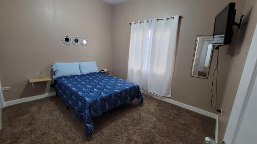 a bedroom with a blue bed and a television at Casa Consulado Gardeno Residencial in Manuel F. Martínez