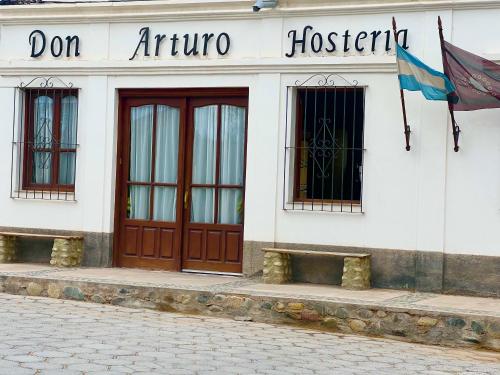 カチにあるHostería Don Arturoの2つのドアと正面に旗がある建物