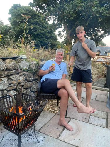 a man standing next to a woman sitting next to a fire at Swallow Bach in Llanddyfnan
