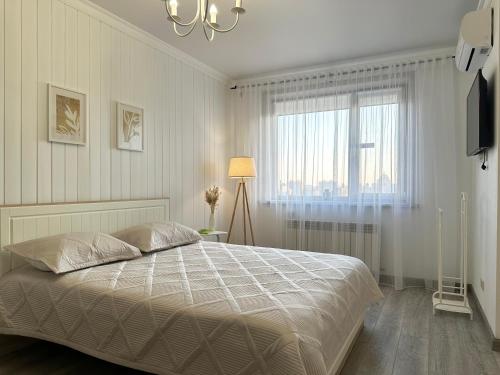 a white bedroom with a bed and a window at ЖК "Light House", 2 in Astana