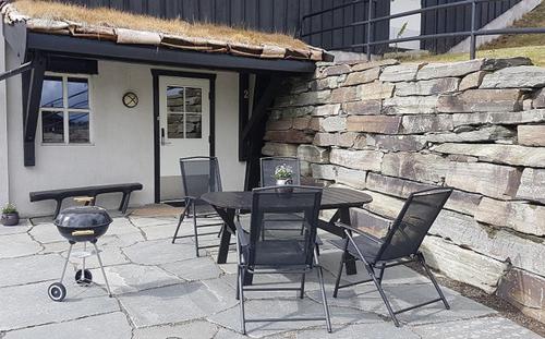 un patio avec une table et des chaises et un mur en pierre dans l'établissement Ro i sentrum, à Beitostøl