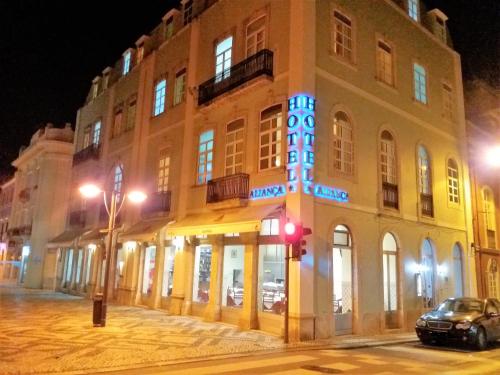 a building with a sign on the side of it at night at Hotel Alianca in Figueira da Foz