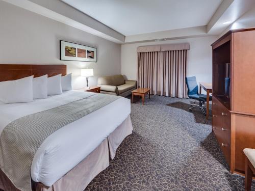 een hotelkamer met een groot bed en een bureau bij Heritage Inn & Suites - Brooks in Brooks