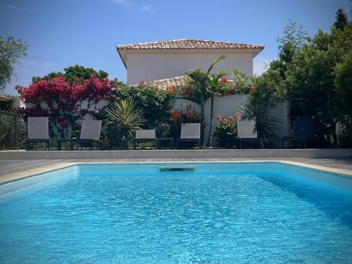- une piscine en face d'une maison fleurie dans l'établissement Villa Maestro Maria Charme Confort et Accueil Chaleureux à 5 min de la plage, à Lecci