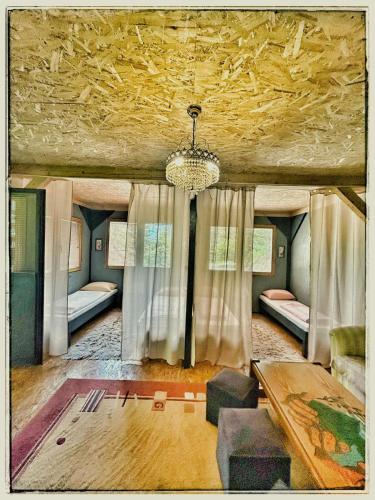a living room with a chandelier and a room with beds at Vila N&M in Visoko
