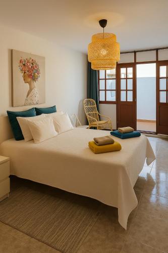 a bedroom with a large white bed with a chair at Villa Buendía in Puerto del Carmen