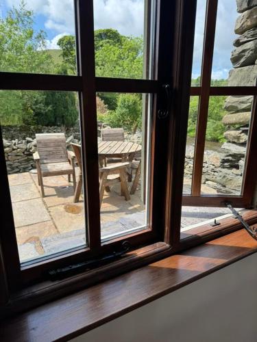 a window with a view of a table and a bench at Oak Tree Cottage nestled in the hills of the Lake District and Yorkshire Dales in Tebay
