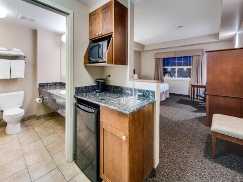 a kitchen with a sink, stove, and refrigerator at Heritage Inn & Suites - Brooks in Brooks