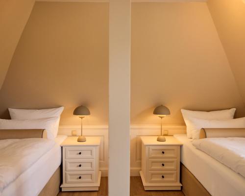 two beds in a room with two lamps on night stands at Watthüs Morsum mit Kamin und traumhaftem Garten in Morsum