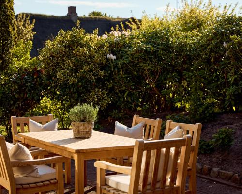 a wooden table and chairs in a garden at Watthüs Morsum mit Kamin und traumhaftem Garten in Morsum