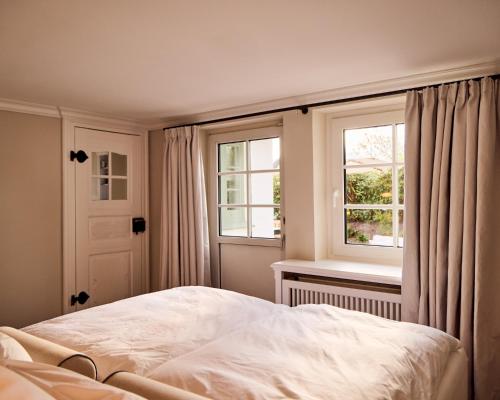 a bedroom with a white bed and two windows at Watthüs Morsum mit Kamin und traumhaftem Garten in Morsum