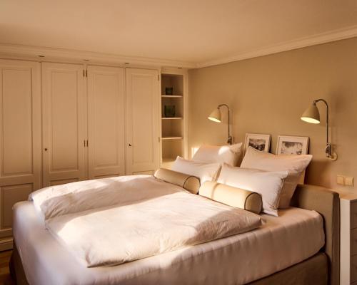 a bedroom with a large white bed with two lamps at Watthüs Morsum mit Kamin und traumhaftem Garten in Morsum