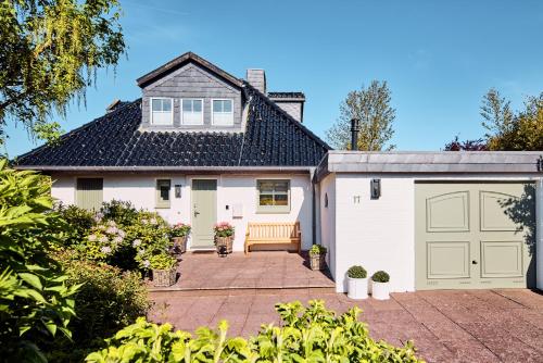 a white house with a garage at Watthüs Morsum mit Kamin und traumhaftem Garten in Morsum
