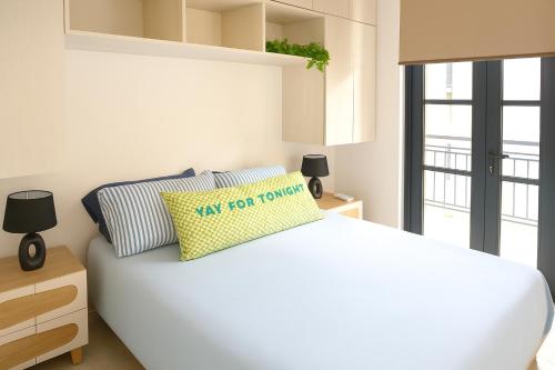 Un dormitorio con una cama blanca con una almohada amarilla. en Lemonade Condo Amplio & Familiar En Casco, en Panamá