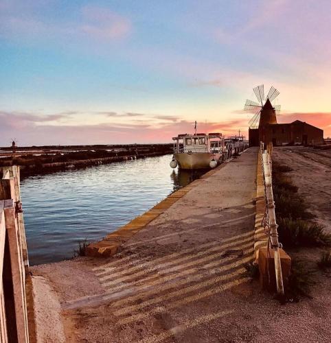 a boat is docked at a dock with a windmill at Il Moro di Ossuna in Trapani